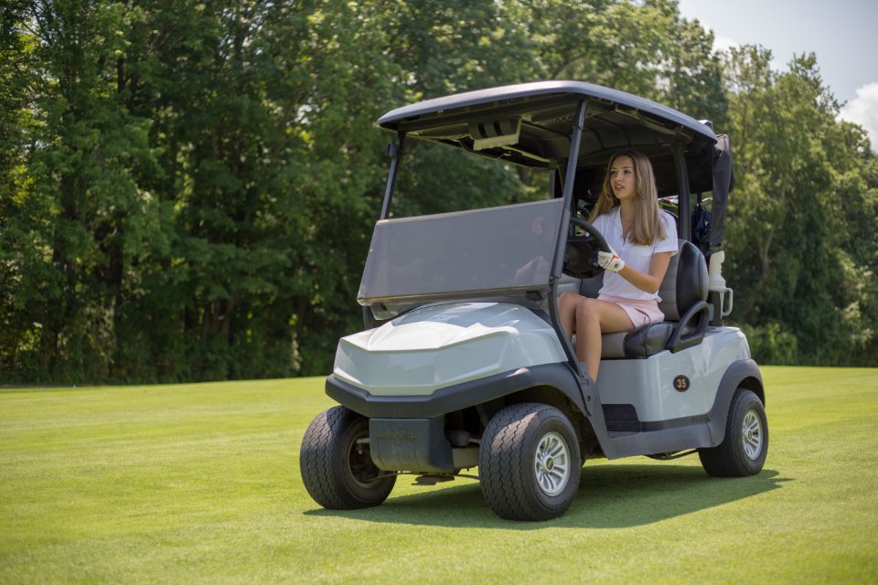An electric golf cart parked beside a course path