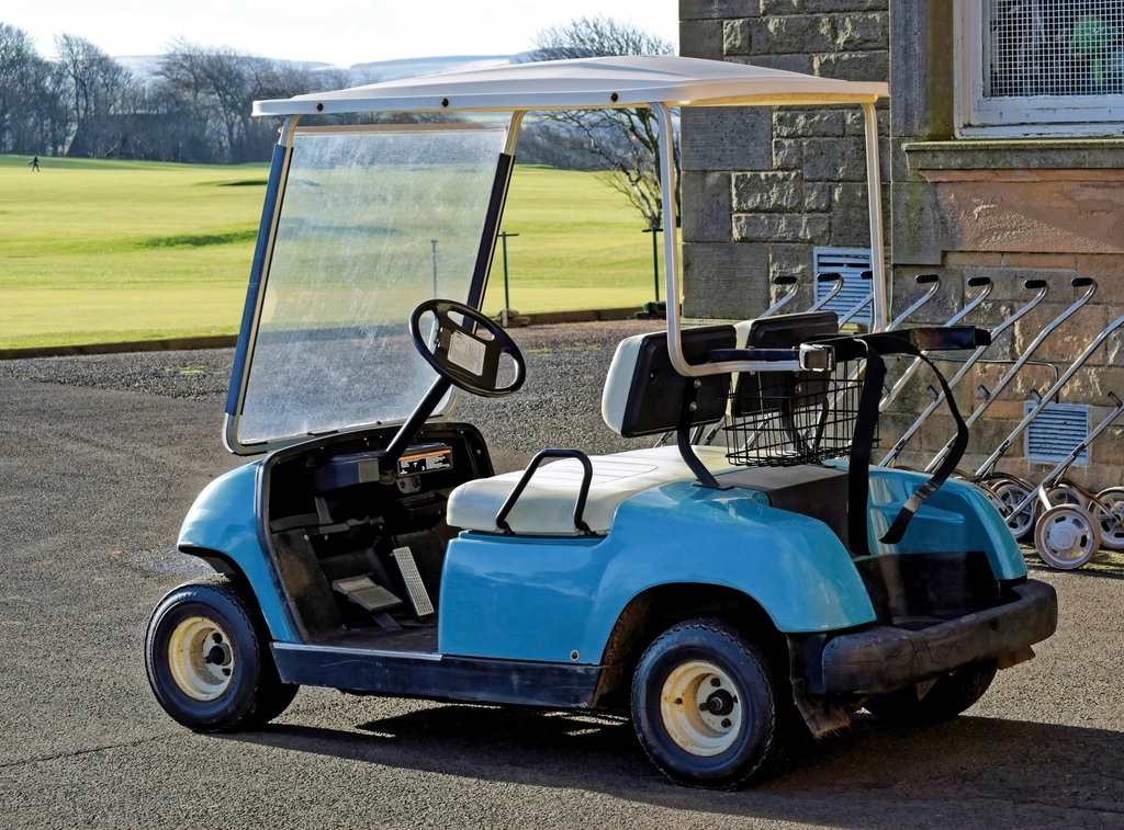 A golf buggy on rough grass
